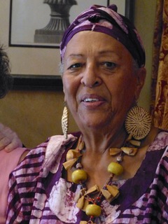 A woman with big earrings and purple outfit.