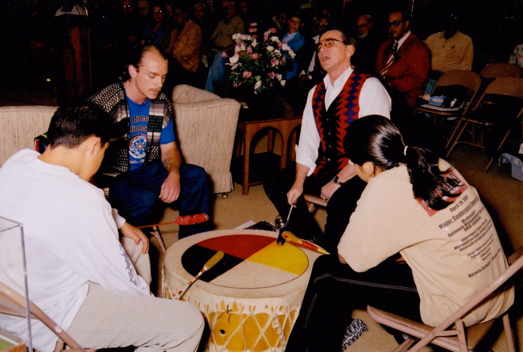 A group of people sitting around a drum.