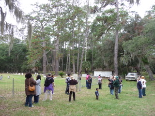 A group of people standing in the grass near trees.